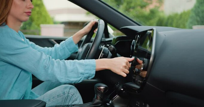 Close up shot hand of woman using touch screen in car setting up the navigation gps application on the touchscreen console.