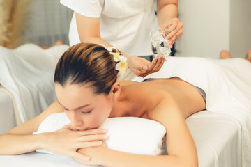 Masseur hands pouring aroma oil on couple's back. Masseuse prepare oil massage procedure for...