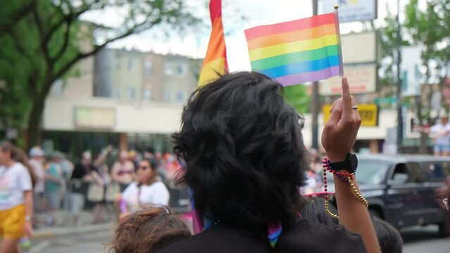 People hold Flag and people at pride parade. Wide shot