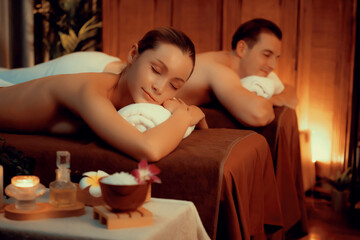 Obraz na płótnie Canvas Caucasian couple customer enjoying relaxing anti-stress spa massage and pampering with beauty skin recreation leisure in warm candle lighting ambient salon spa at luxury resort or hotel. Quiescent