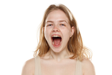 Portrait of young beautiful blonde woman with no makeup and open mouth on white background