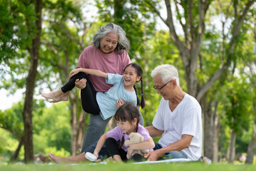 Fototapeta premium Happy Asian family children having fun and playing with her grandparents in the park