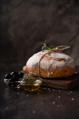 Freshly baked sourdough ciabatta bread with olives and rosemary on a black rustic table. Artisan bread