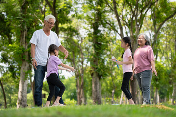 Happy Asian family children having fun and playing with her grandparents in the park