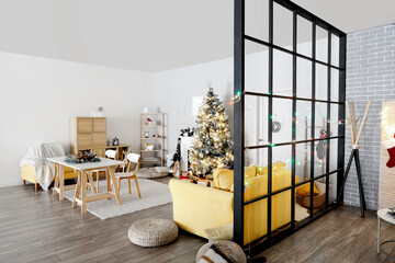Interior of living room with Christmas tree, sofa and dining table