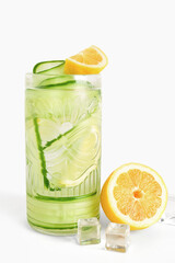 Glass of lemonade with cucumber on white background