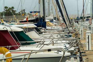 Sailboats and yachts moored in the dock of the port on a rainy day.