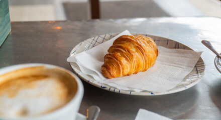Closeup, a crispy puff pastry bun served on a plate, on the cafeteria table