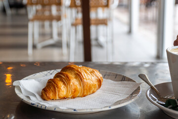 Closeup, a crispy puff pastry bun served on a plate, on the cafeteria table
