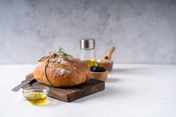 Freshly baked sourdough ciabatta bread with olives and rosemary on a white abstract table. Artisan...