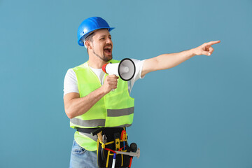 Male builder shouting into megaphone on blue background