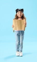 Cute little girl dressed as pirate with treasure map on blue background
