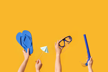 Many hands holding beach accessories on yellow background