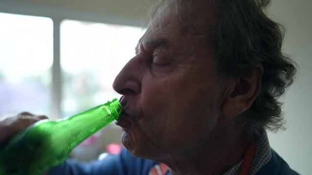 Senior man drinking bottle of beer, profile close-up of person sipping alcoholic beverage