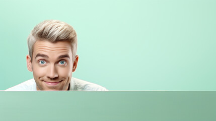 text space for advertising with funny part as portrait of a blond male model peeking over a colored panal