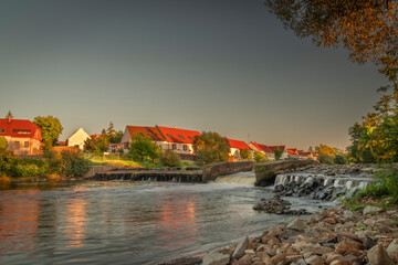 Big weir in Budweis with blue sky and countryside buildings in sunset evening
