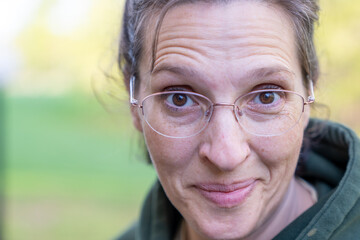 Empowered 51-year-old woman rocking a stylish green hoodie, bathed in warm, natural light. Ageless beauty and confidence.