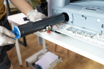 printer repair technician. A male handyman inspects a printer before starting repairs at the service center.