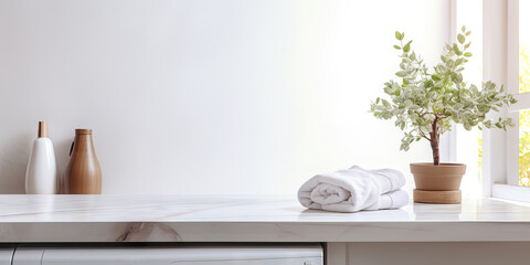 White marble countertop with a plant, towels, and vases in a bright room.