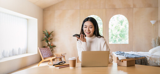 Portrait of asian business woman talk on smartphone working on notebook laptop home office. Beautiful girl at desk computer take home order. Startup business online sme telemarketing.