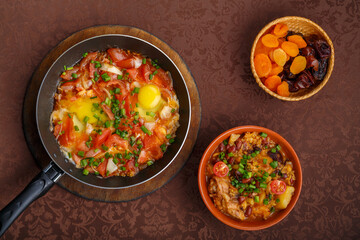 hot shakshuka in a frying pan sprinkled with green onions and chelnt on the sabbath table.