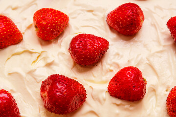 Fresh juicy red strawberries with green leaves in thick whipped cream close-up