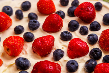 Fresh juicy red strawberries and blueberries in heavy whipped cream close-up