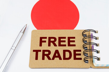 On the flag of Japan lies a pen and a notebook with the inscription - free trade