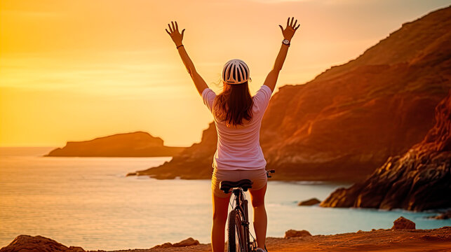  Happy woman with open arms on bicycle at sunset