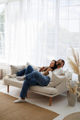 Joyful young multiethnic couple relaxing and cuddling on couch in living room 