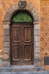 Fototapeta na wymiar old vintage wooden door with stone trim and decorative steal awning and colorful patterned wall