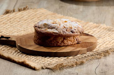 Round pastry with almonds and butter sprinkled with powdered sugar on the table, puff pastry