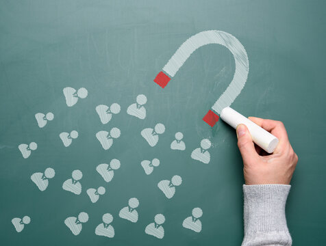 Magnet and icons drawn with white chalk. The concept of attracting new customers and retaining the audience