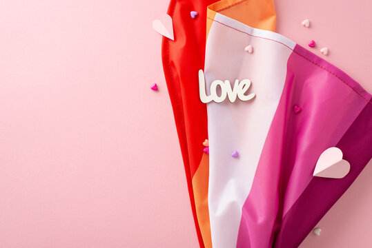 Celebrate International Lesbian Day with a top-down view image of the Lesbian Pride flag, small hearts, "love" message on a pastel pink canvas with empty space