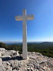 The Cross of Jesus rises on the mountain. Big cross against the background of the sea. Croatia, Ugljan island, near the ruins of the fortress, September 7, 2023.