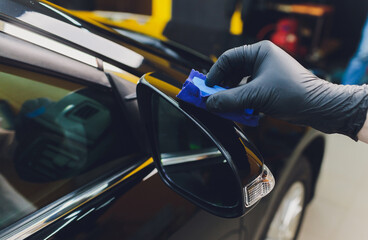 Car detailing - Man applies nano protective coating to the car. Selective focus.
