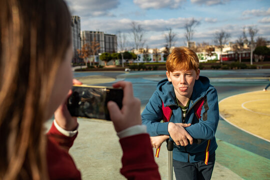 Young boy and girl friends taking pictures with a smartphone in a skate park