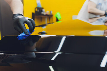 Car detailing - Man applies nano protective coating to the car. Selective focus.
