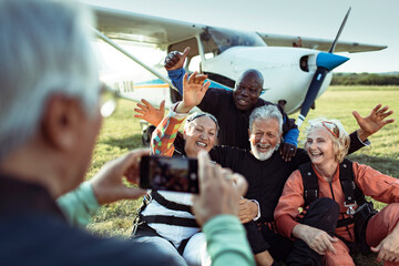 Group of senior friends taking a selfie after skydiving for the first time and completing their bucket list