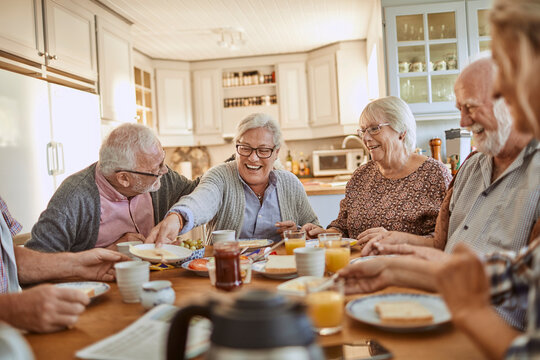 Senior friends having breakfast together in the kitchen in the morning