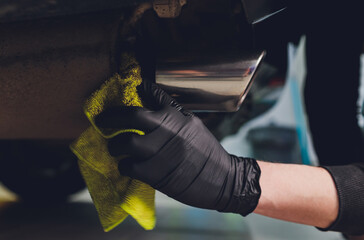 Car exhaust pipe with soap. Car wash background. close-up of a green rag