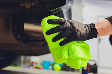 Car exhaust pipe with soap. Car wash background. close-up of a green rag