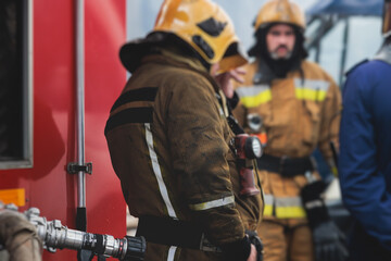 Group of fire men in protective uniform during fire fighting operation in the city streets,...