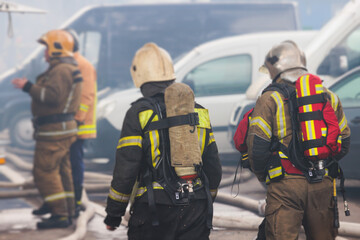 Group of fire men in protective uniform during fire fighting operation in the city streets,...