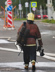 Group of fire men in protective uniform during fire fighting operation in the city streets, firefighters brigade with the fire engine truck vehicle in the background, emergency and rescue service