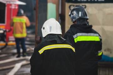 Group of fire men in protective uniform during fire fighting operation in the city streets,...