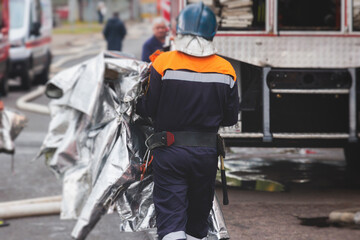 Group of fire men in protective uniform during fire fighting operation in the city streets,...