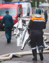 Group of fire men in protective uniform during fire fighting operation in the city streets,...