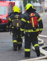 Group of fire men in protective uniform during fire fighting operation in the city streets,...