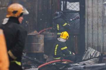 Group of fire men in protective uniform during fire fighting operation in the city streets, firefighters brigade with the fire engine truck vehicle in the background, emergency and rescue service